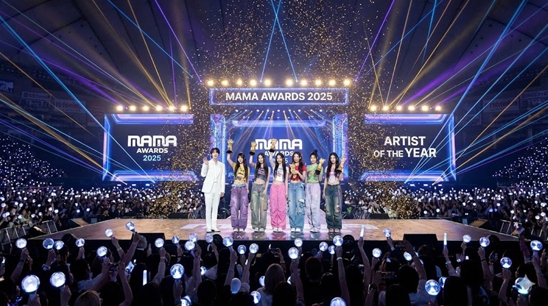 2025 MAMA 어워즈 무대에서 대상을 수상한 BTS 진과 뉴진스 멤버들이 트로피를 들고 환호하는 모습과 화려한 꽃가루